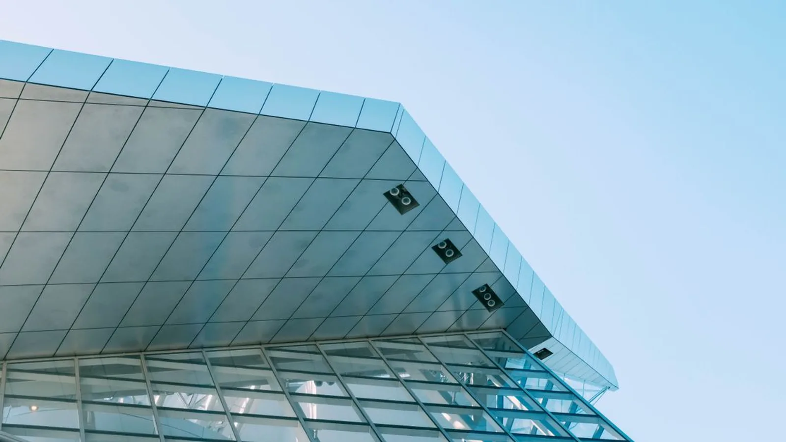 Low-angle shot of a modern urban building with glass panels and steel structure.