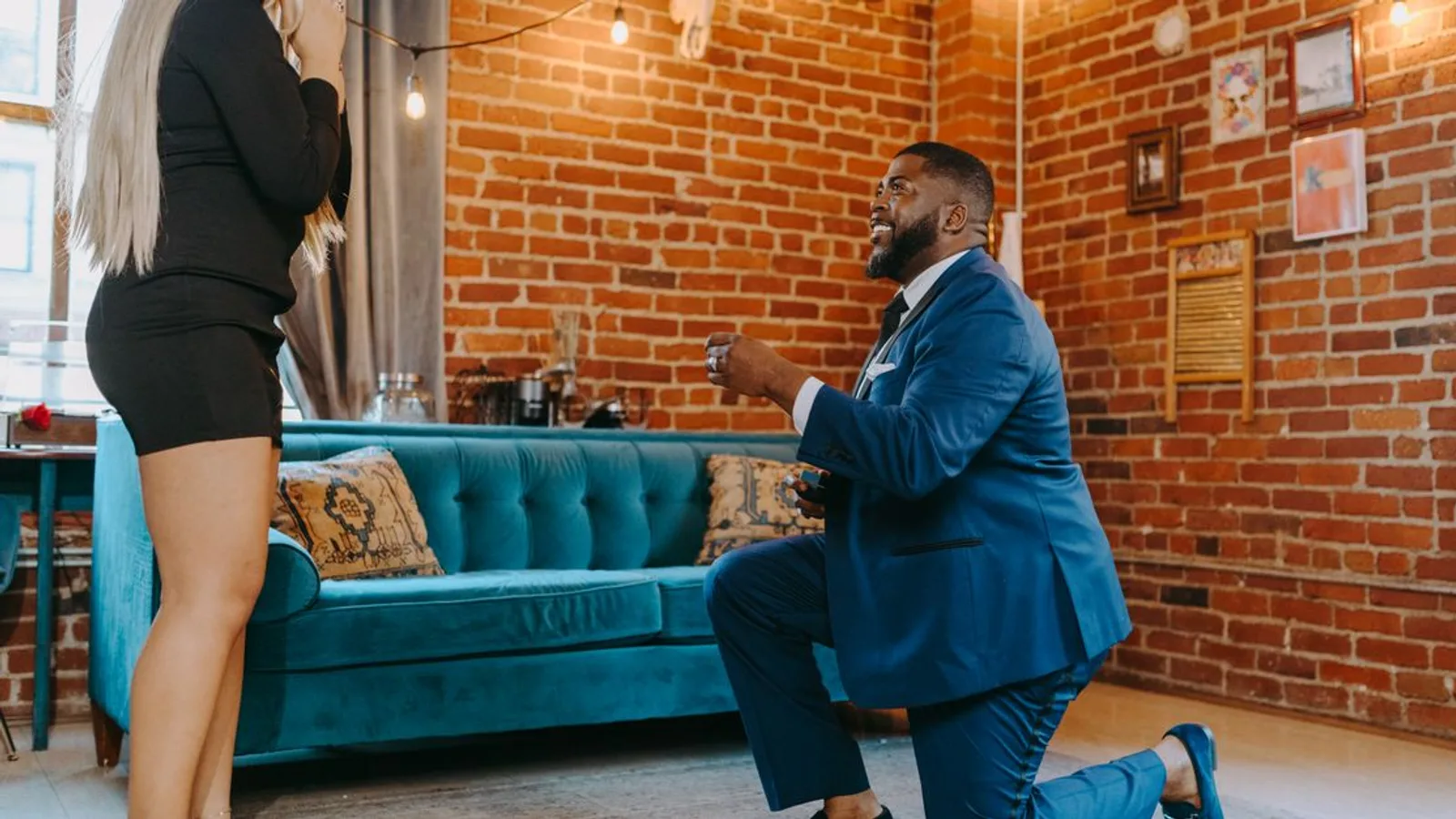 A man proposes to a woman indoors, capturing a romantic and intimate moment.