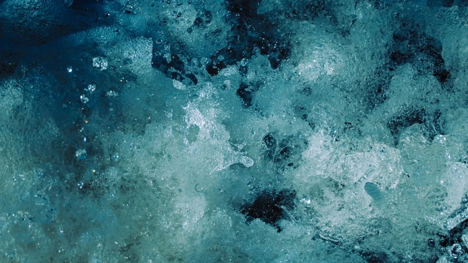 Close-up of dynamic blue water splash and bubbles creating abstract patterns.