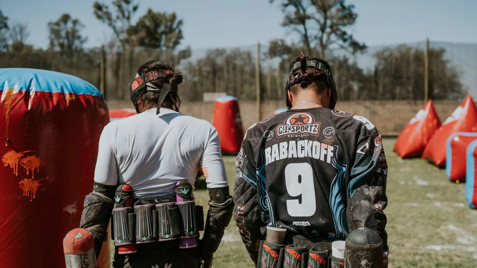 Two players in action on a paintball field, equipped and ready for the game.