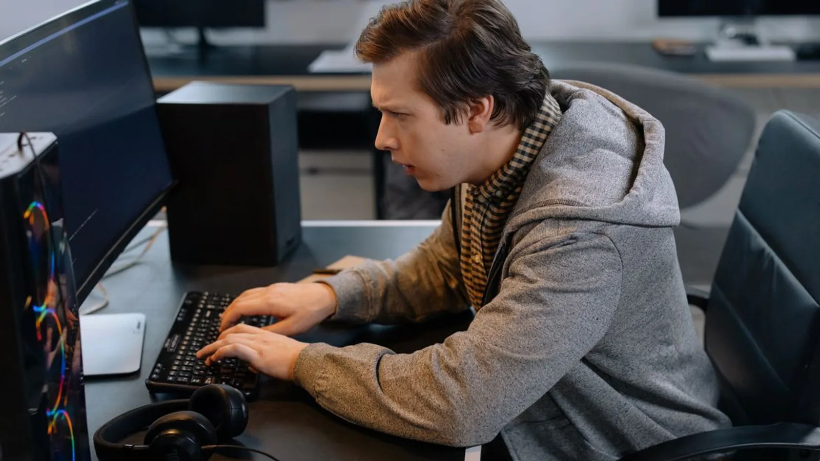 Focused male programmer working at office desk, coding efficiently.