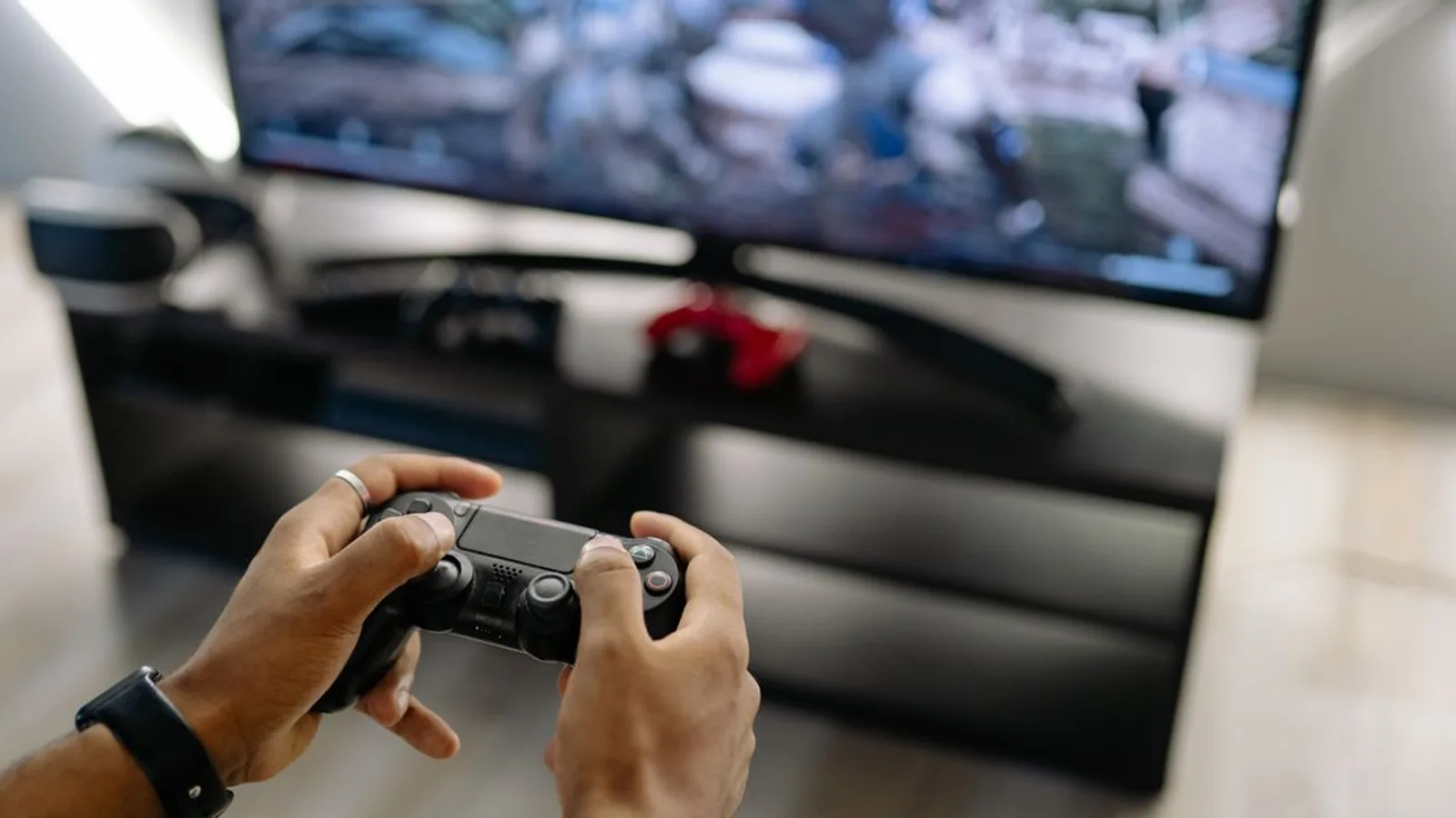 Close-up of hands holding a gaming controller while playing video games indoors.